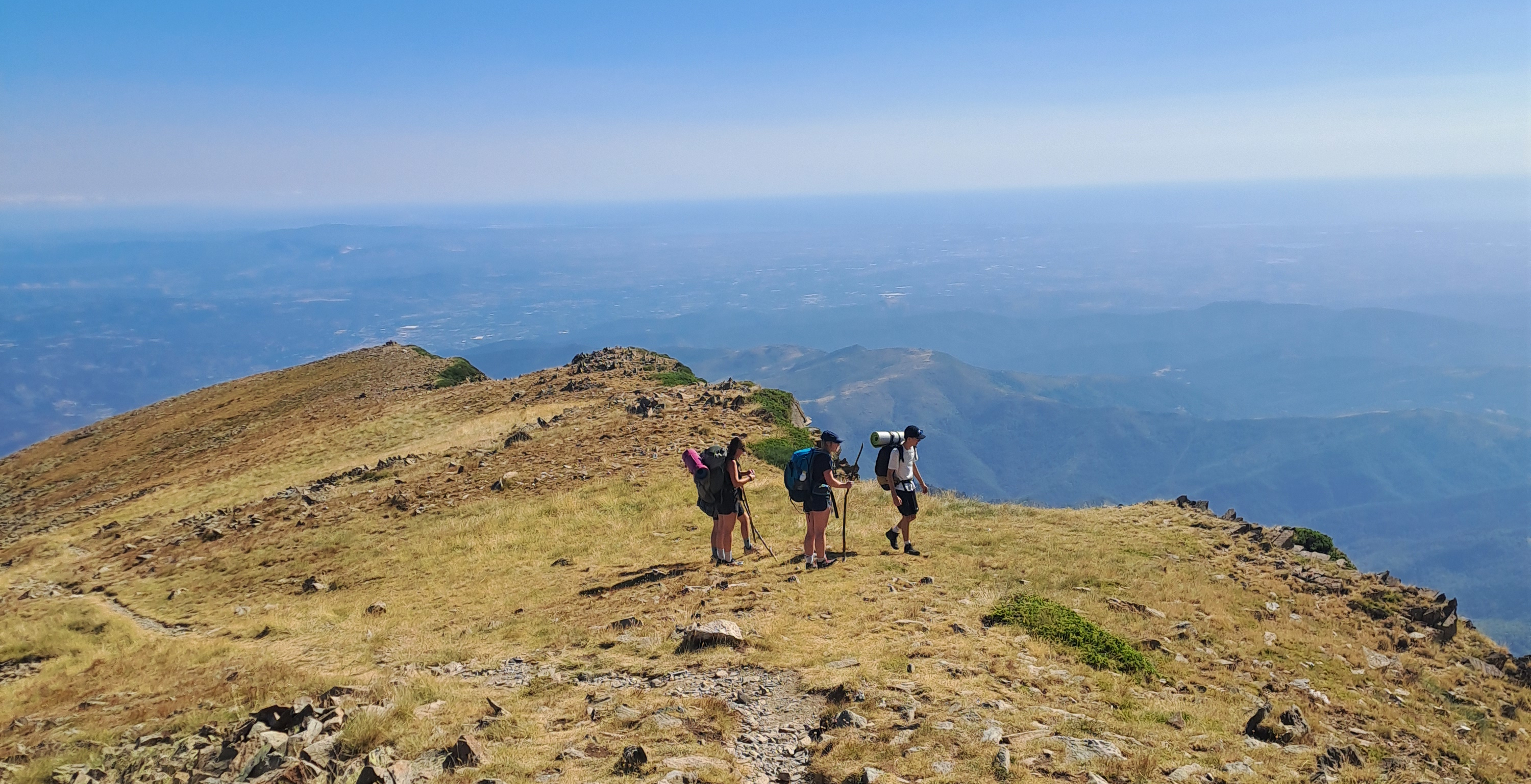 Des randonneurs sur une crête avec une vue dégagées et très haute donnant la côte